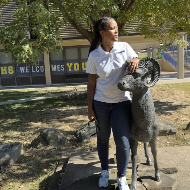 Mahogany Henderson, founder of Most Precious Dreams Foundation, standing beside the Riverview Rams statue at Riverview Gardens High School in St. Louis, Missouri.